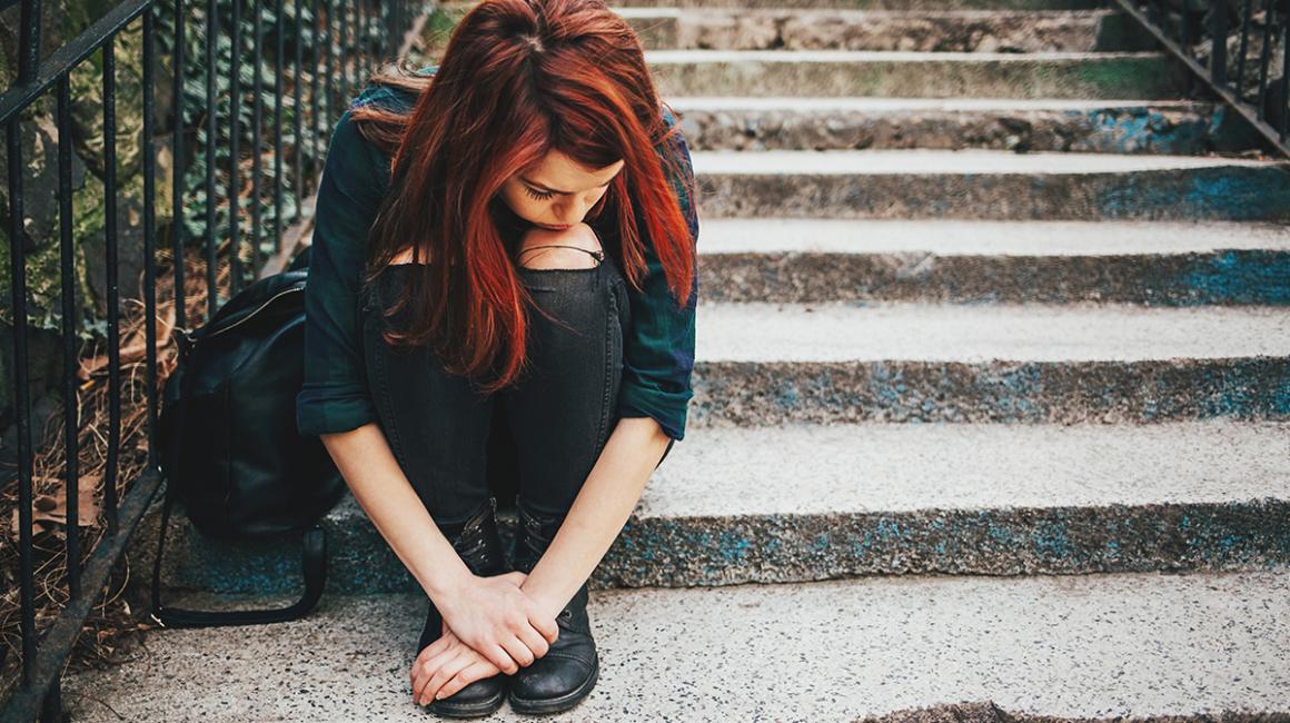 Smutna dziewczynka siedzi na kamiennych schodach