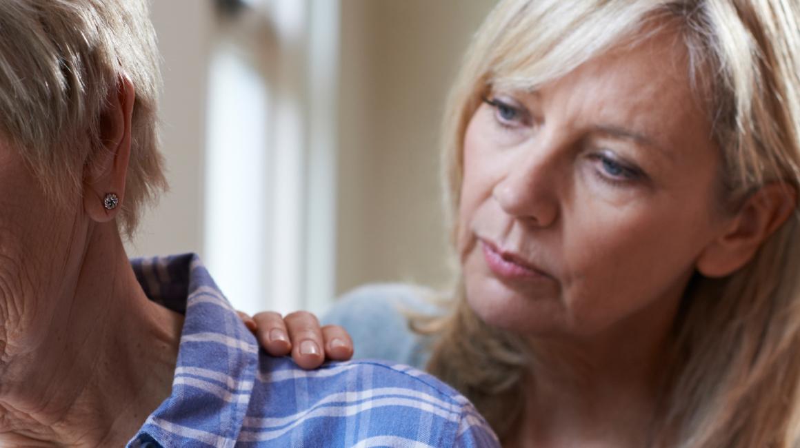 Córka kładzie rękę na ramieniu smutnej matki, starszej pani