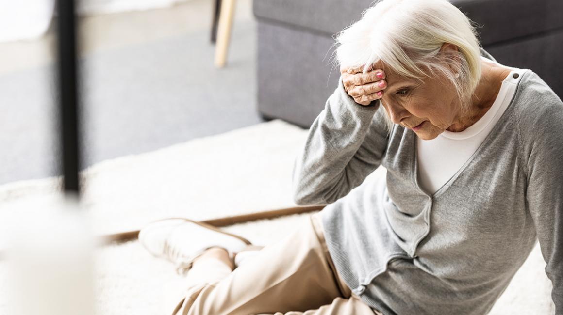 Starsza kobieta trzyma się za głowę, upadła