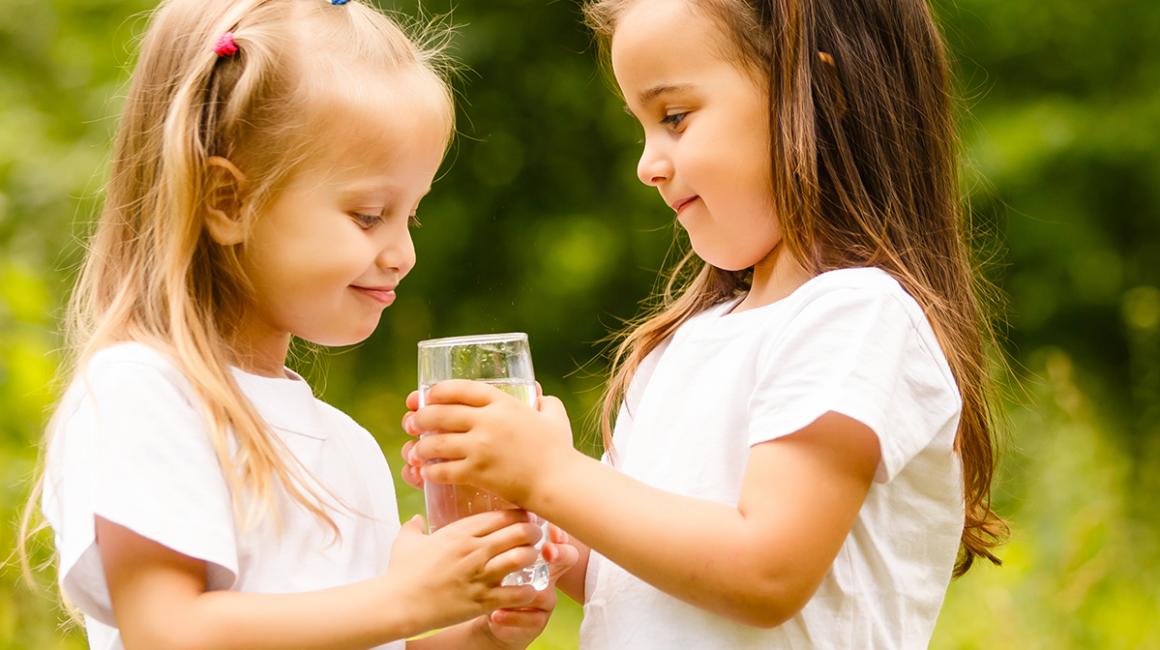Dziewczynka podaje szklankę wody koleżance