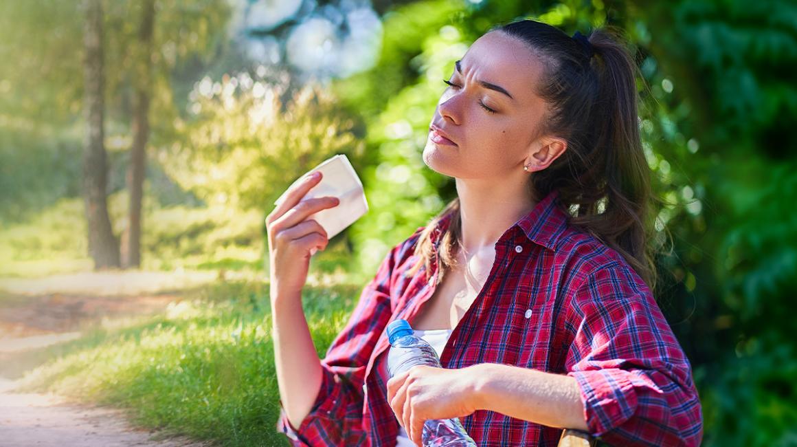 Kobieta wachluje się kartką w parku