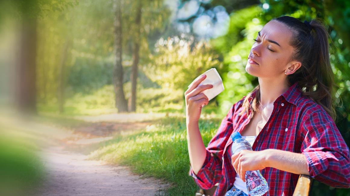 Kobieta wachluje się kartką w parku