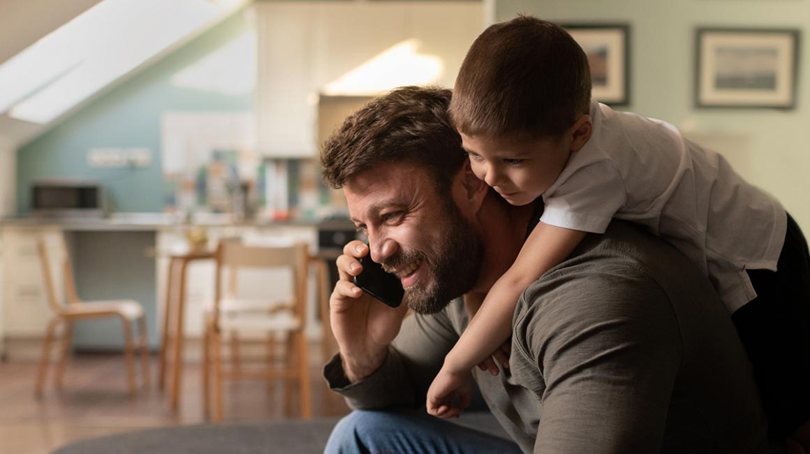 Syn wchodzi na plecy ojcu, który rozmawia przez telefon