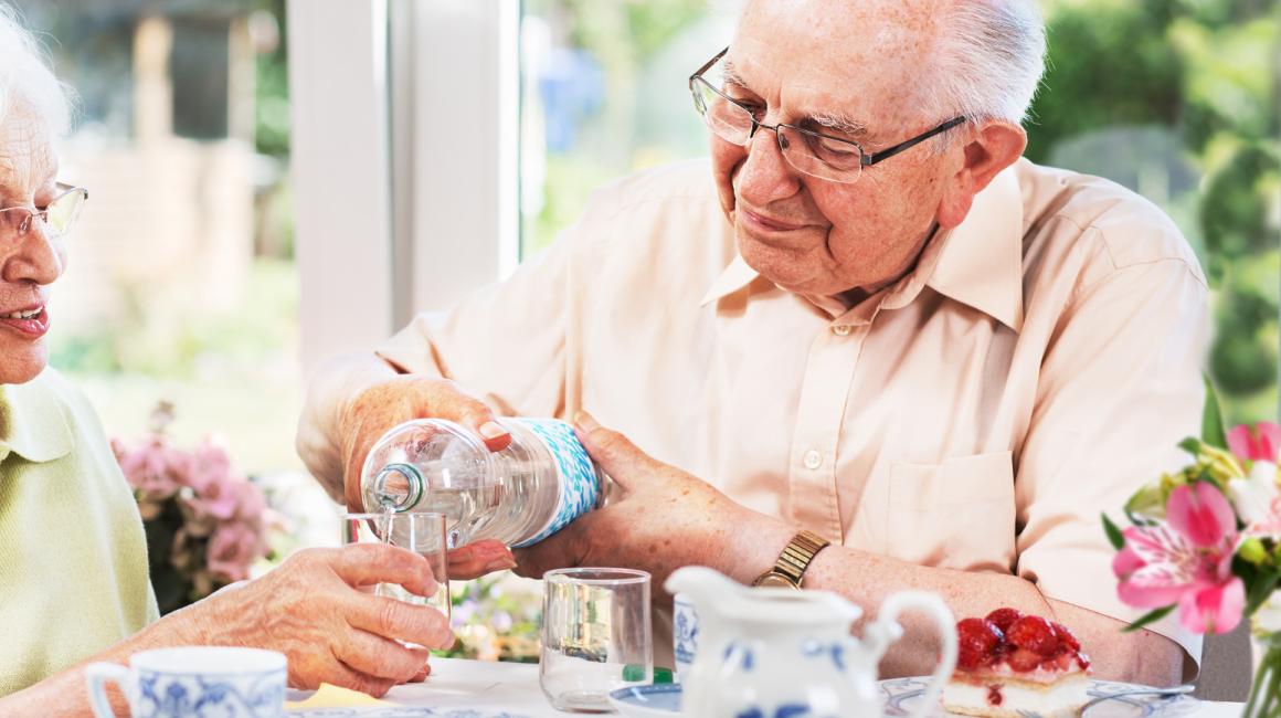 Starszy pan nalewa żonie wodę