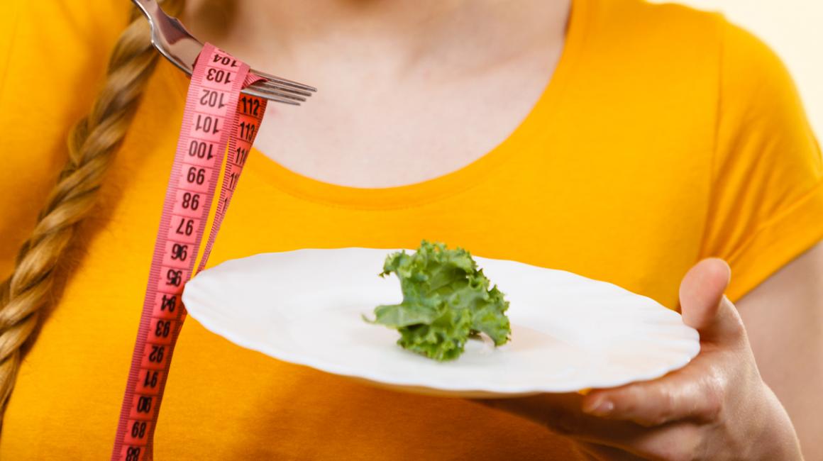 Talerz z liściem sałaty i centymetr nawinięty na widelec