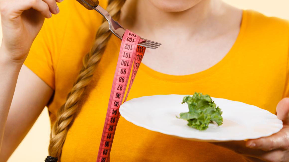 Talerz z liściem sałaty i centymetr nawinięty na widelec