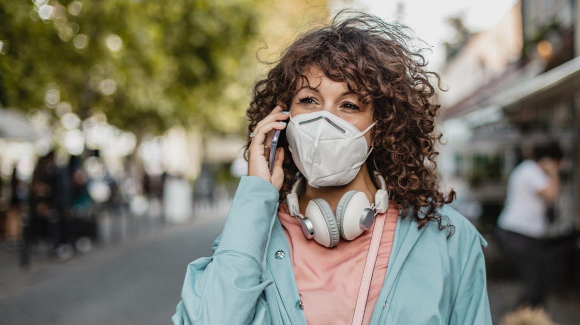 kobieta w maseczce rozmawia przez telefon na ulicy