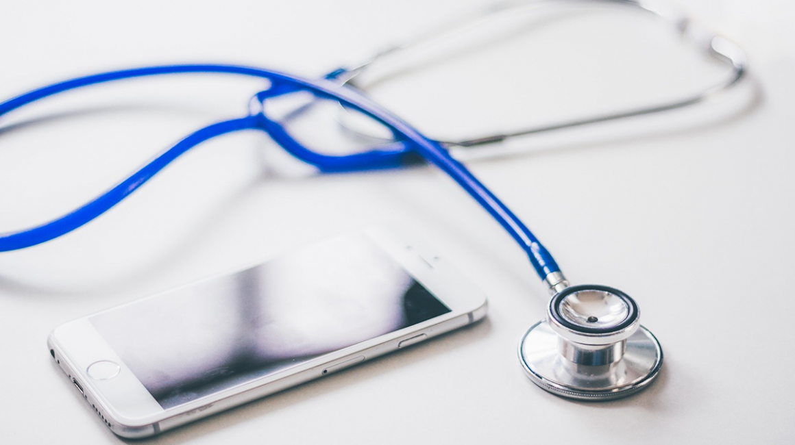 Leżące na gładkiej powierzchni telefon komórkowy i stetoskop