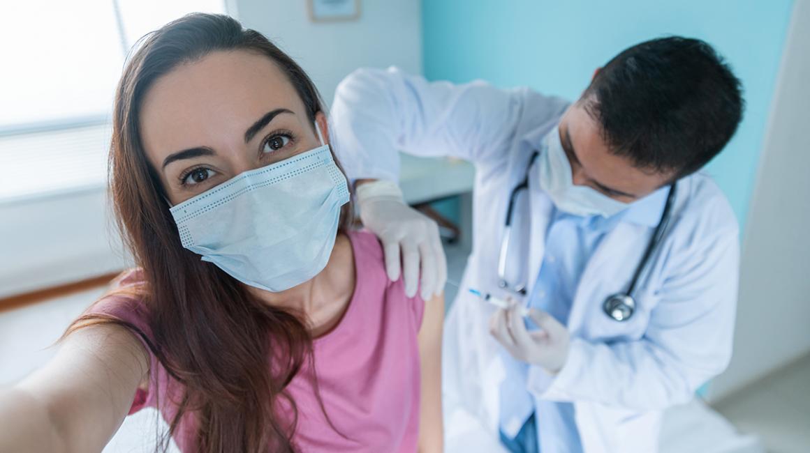 Młoda kobieta  w maseczce otrzymuje szczepionkę