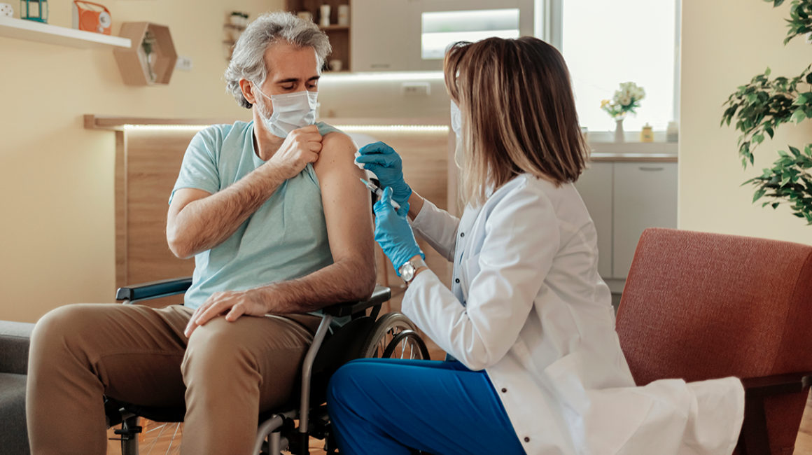 Pielęgniarka szczepi pacjenta na wózku
