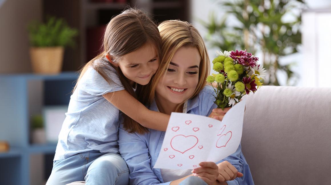 Dziewczynka przytula się do matki, która ogląda laurkę