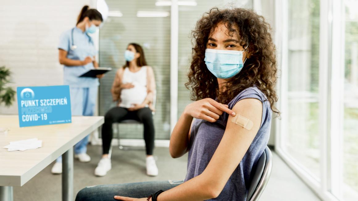 Dziewczyna pokazuje na plaster po szczepieniu