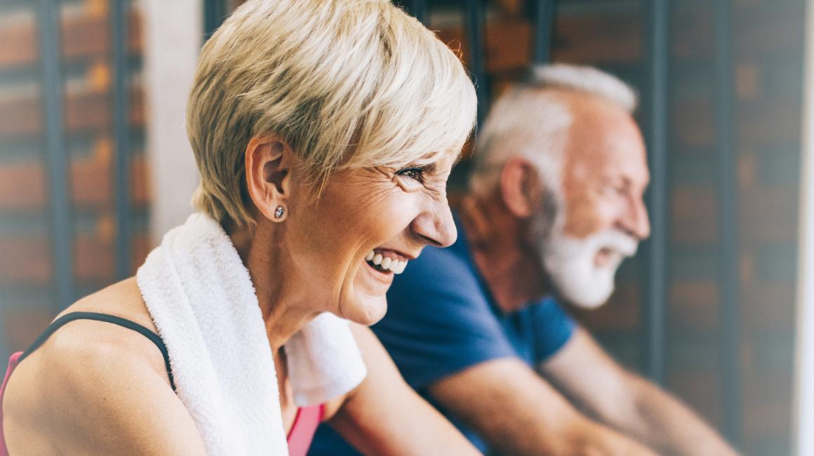 Starsza para ćwiczy na rowerkach stacjonarnych 