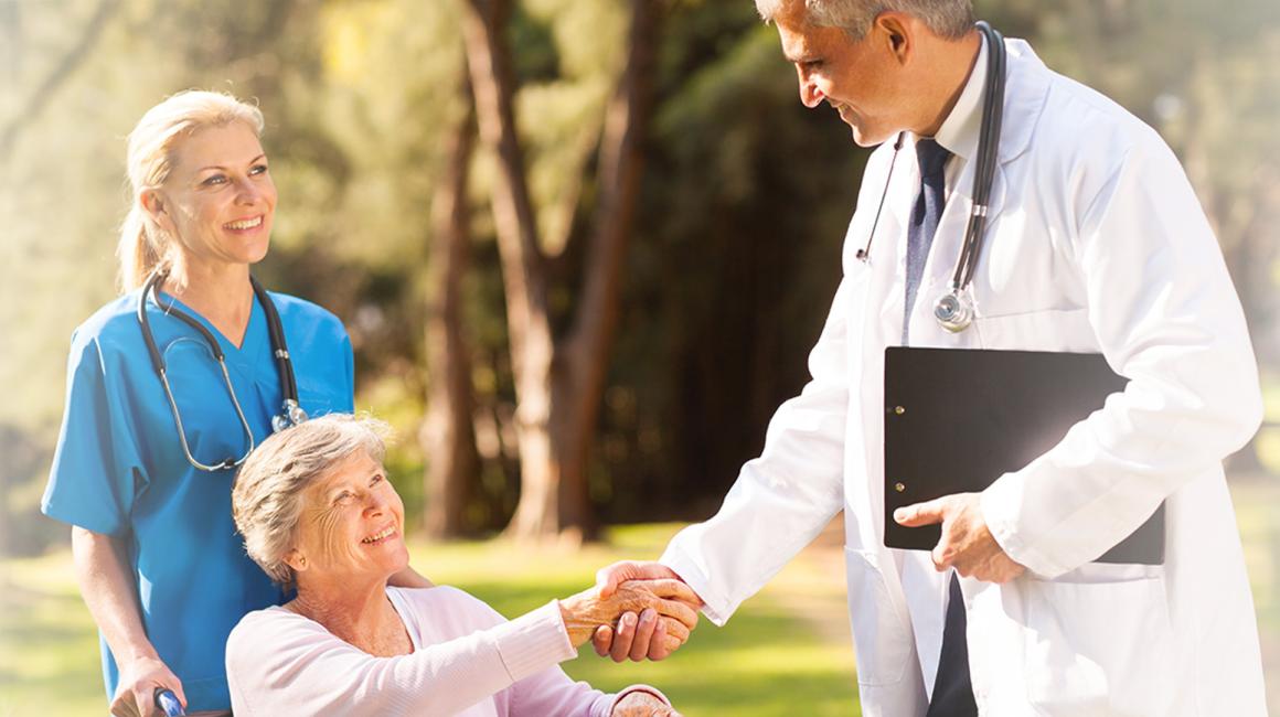 Starsza kobieta na wózku w otoczeniu lekarza i pielęgniarki