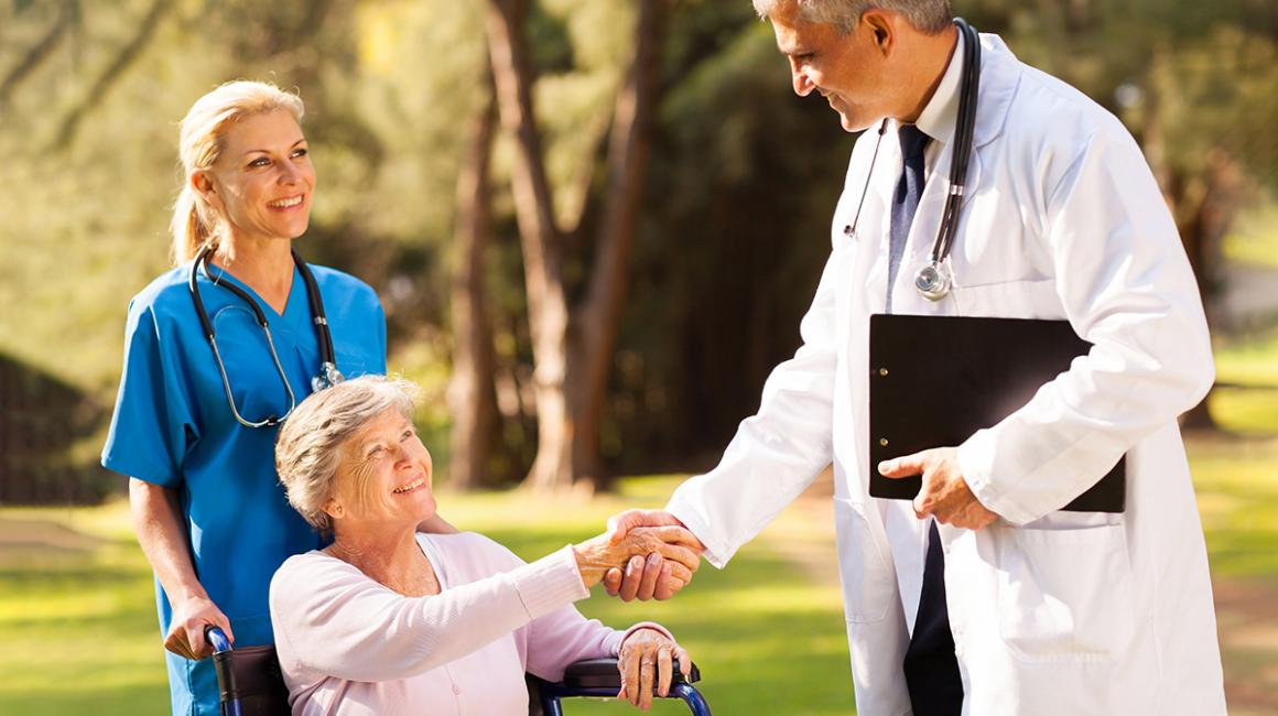 Starsza kobieta na wózku w otoczeniu lekarza i pielęgniarki