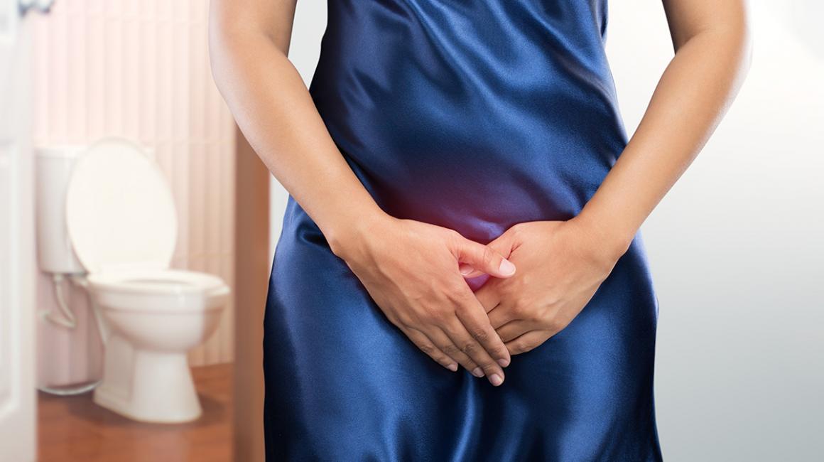 Wykadrowana kobieta z rękoma na układzie moczowym. Z lewej strony w tle toaleta.