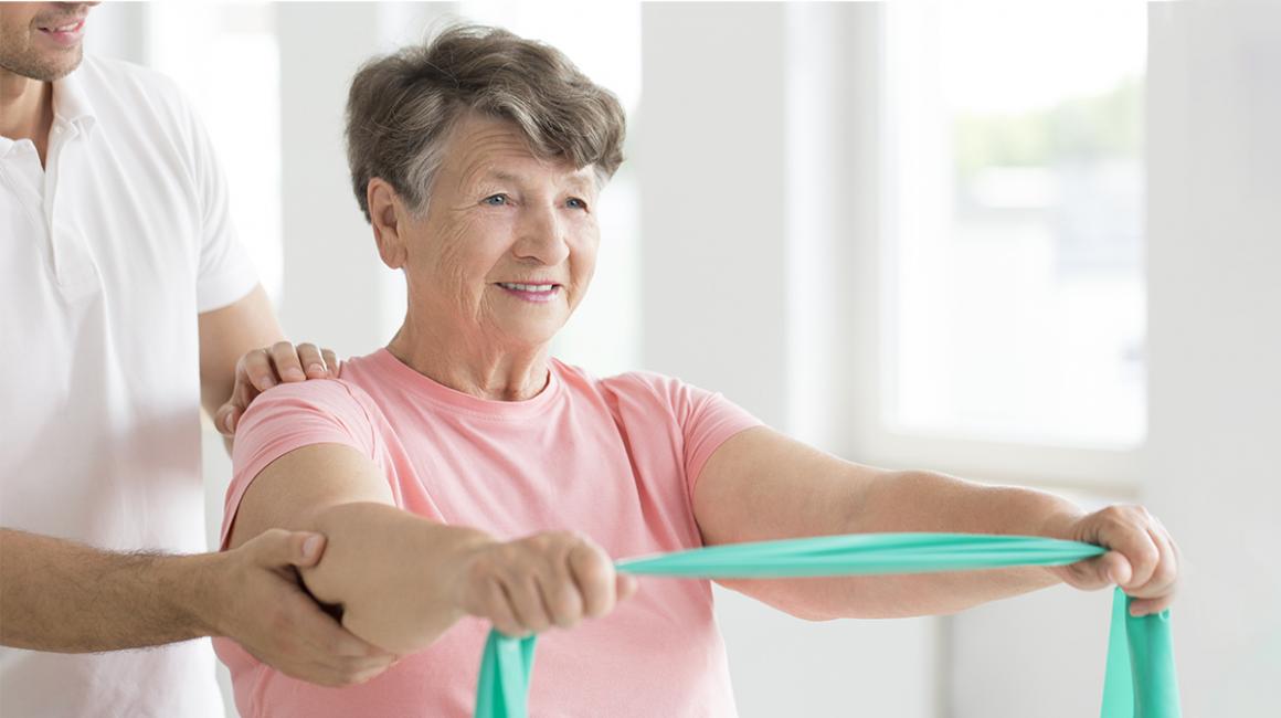 Starsza pani ćwiczy pod okiem fizjoterapeuty