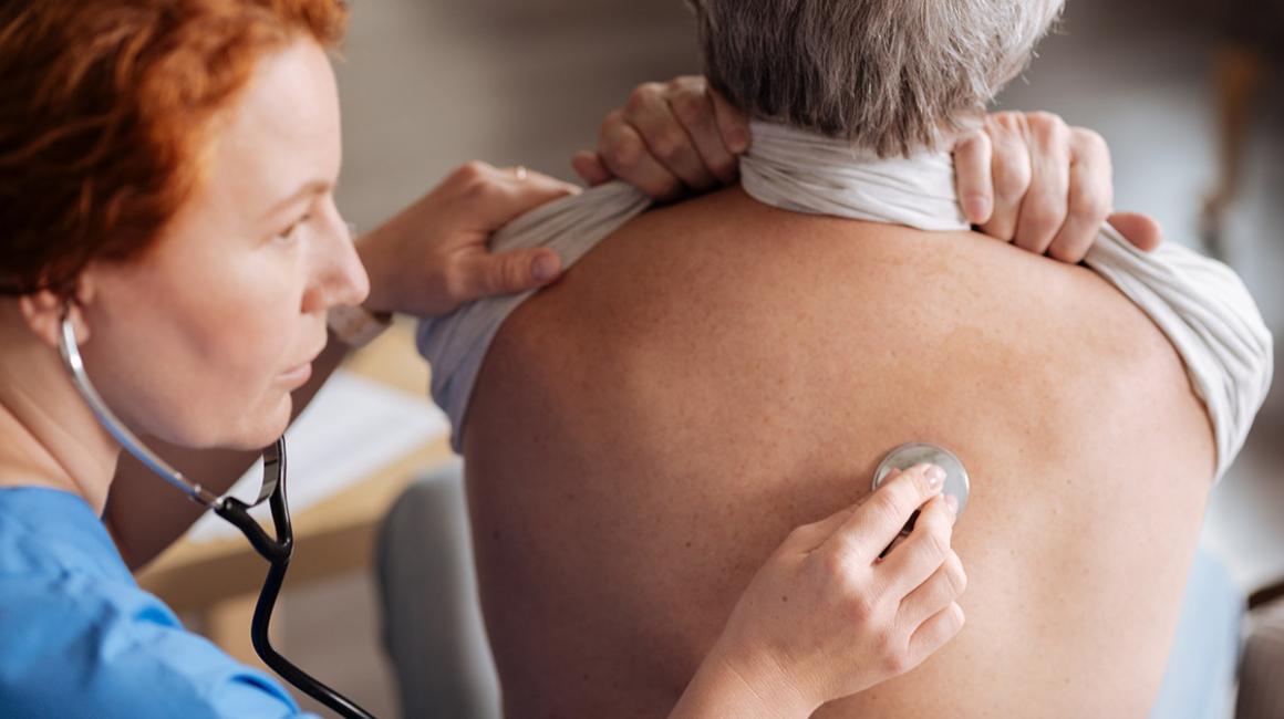 Pielęgniarka osłuchuje plecy badanego mężczyzny