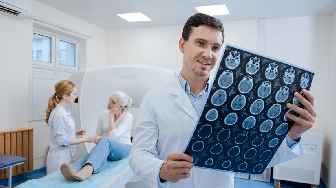 Lekarz przegląda wyniki tomografii komputerowej, w tle pacjentka z pielęgniarką