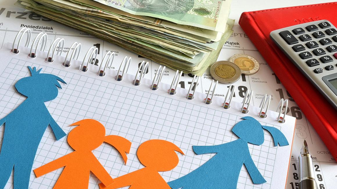 Na blacie leży zeszyt, pieniądze i kalkulator