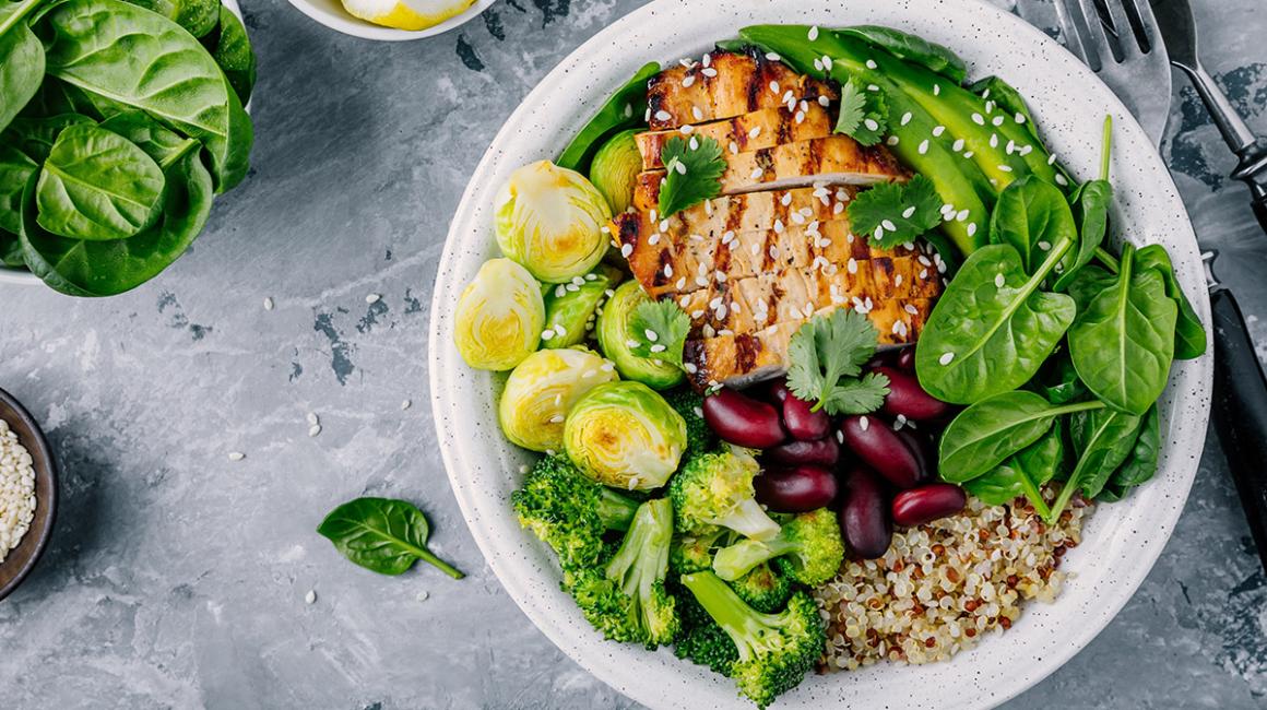 Talerz z jedzeniem, a na nim: brukselka, brokuł, szpinak, fasola, kasza i grillowana pierś kurczaka