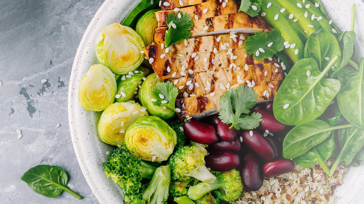 Talerz z jedzeniem, a na nim: brukselka, brokuł, szpinak, fasola, kasza i grillowana pierś kurczaka