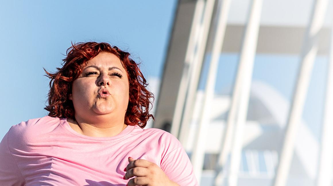 Biegnąca kobieta z nadwagą. W tle nowoczesny most