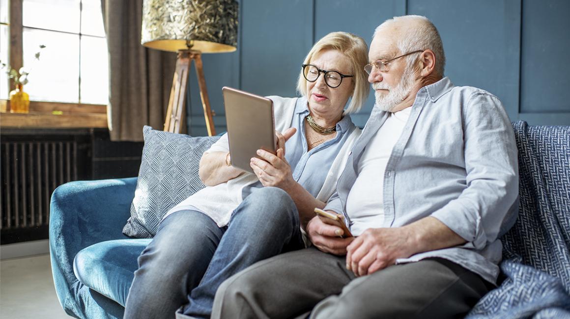 Starsza para na kanapie patrzy na tablet
