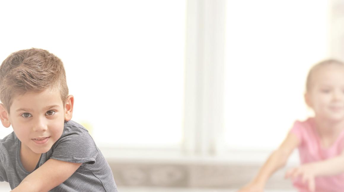 Dzieci na sali gimnastycznej rozciągające nogi w siadzie.