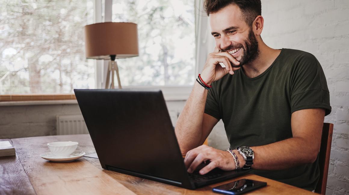 Uśmiechnięty trzydziestolatek przed komputerem