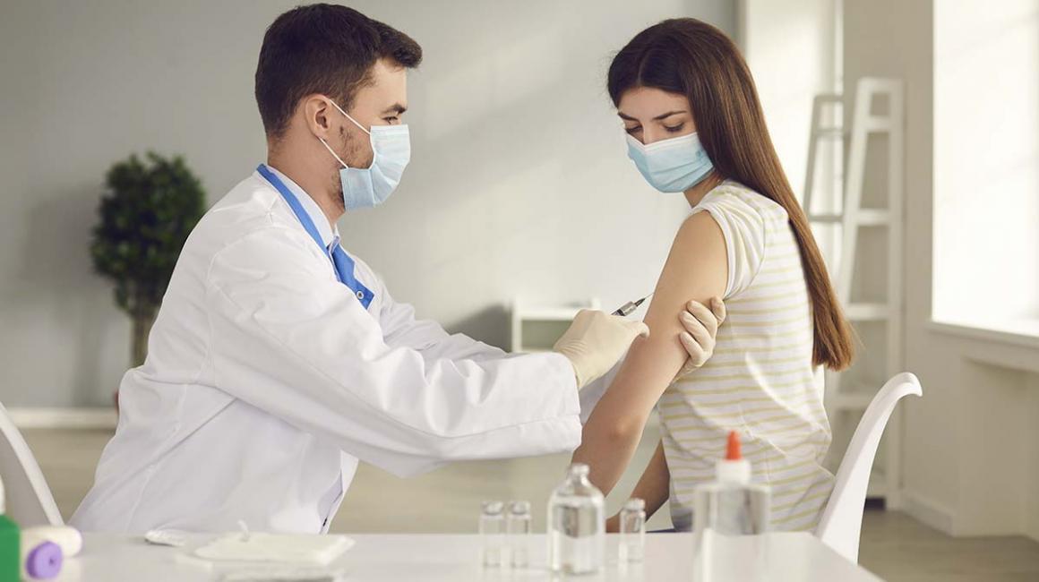 Młoda kobieta  w maseczce otrzymuje szczepionkę