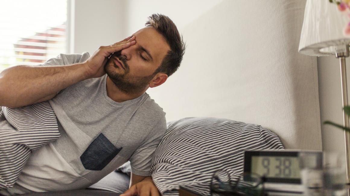 Zmęczony, zaspany mężczyzna wstaje z łóżka.