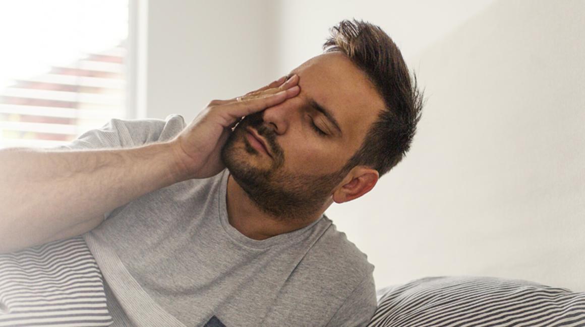 Zmęczony, zaspany mężczyzna wstaje z łóżka.