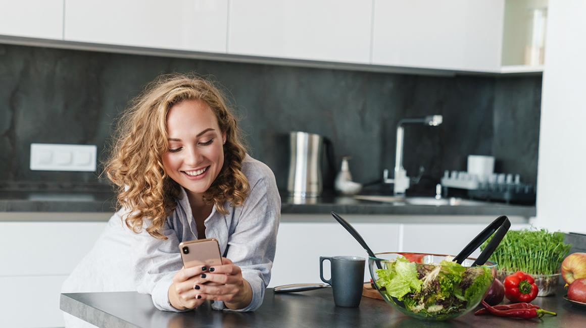 Kobieta w kuchni patrzy na telefon