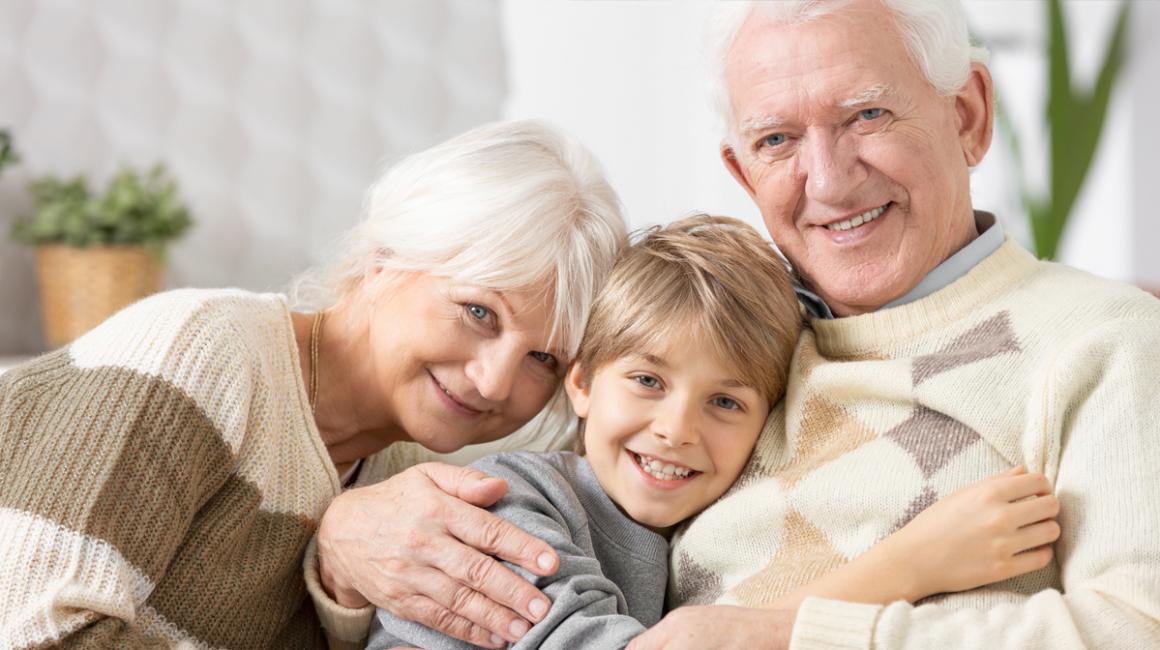Przytuleni od lewej babcia, wnuczek, dziadek. Siedzą, patrzą na wprost.