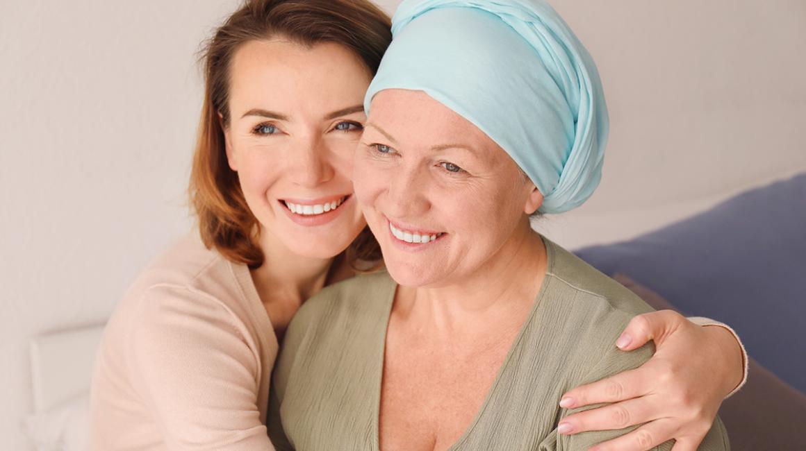 Młodsza kobieta obejmuje starszą, które głowa jest owinięta chustą