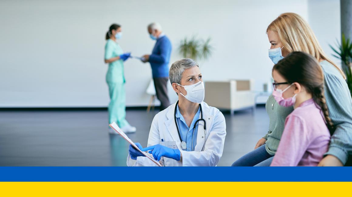 Lekarz pokazuje kartę matce z dzieckiem, flaga ukraińska na dole