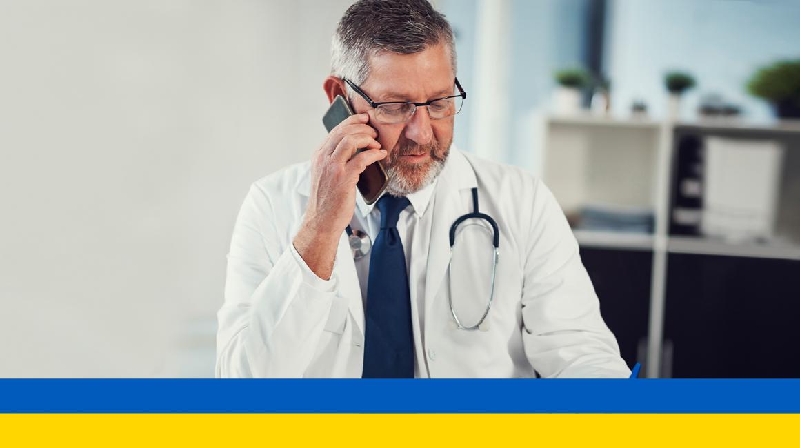 Lekarz rozmawiający przez telefon, na dole ukraińska flaga