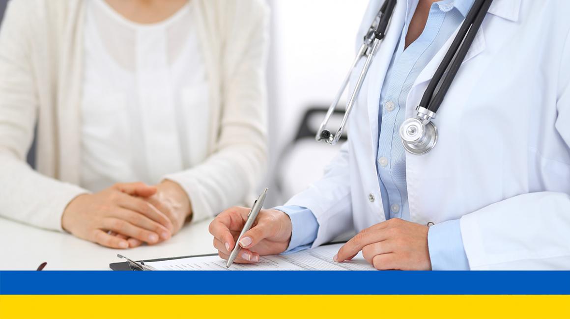 Kobieta u lekarza. Lekarz wypelnia formularz. Na dole flaga Ukrainy.