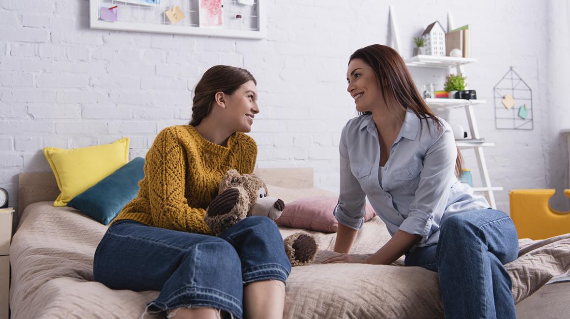 Matka z nastoletnią córką rozmawiają siedząc na tapczanie