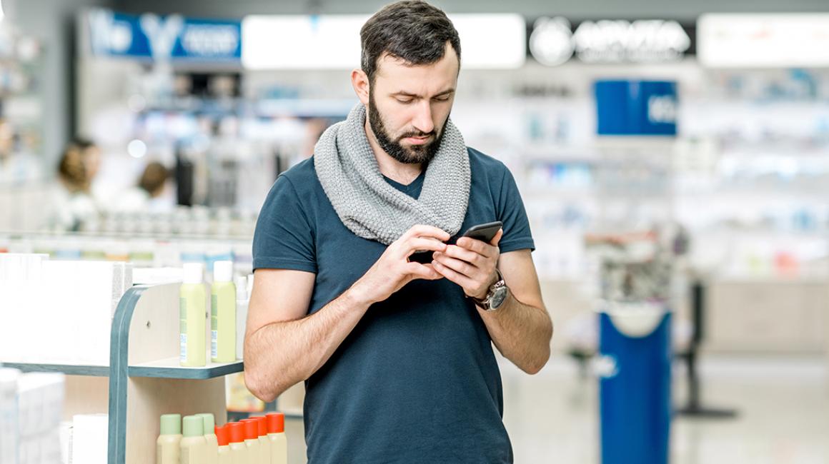 Mężczyzna w aptece patrzy na komórkę