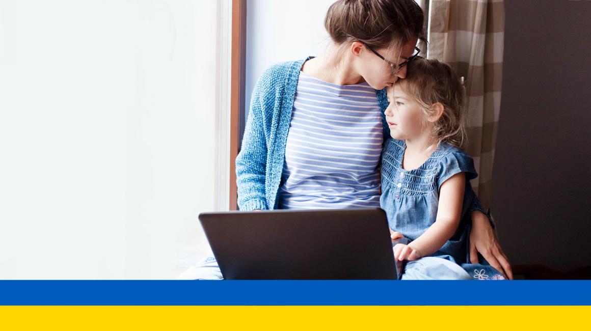 Matka przed komputerem całuje malucha w głowę