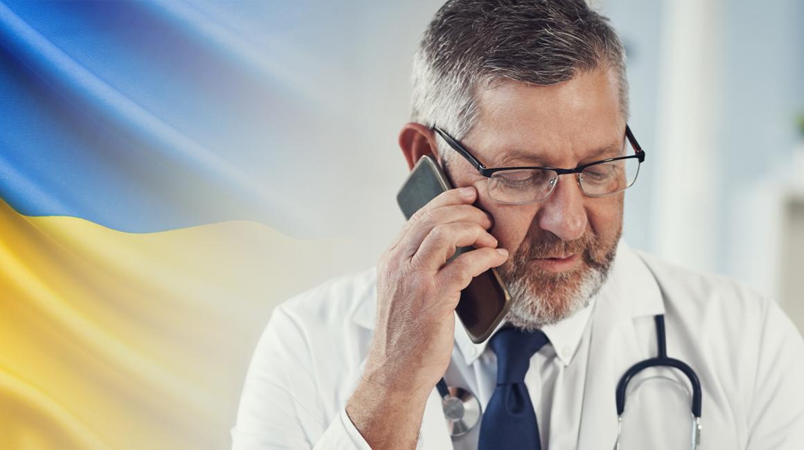 Lekarz rozmawiający przez telefon, z lewej strony ukraińska flaga
