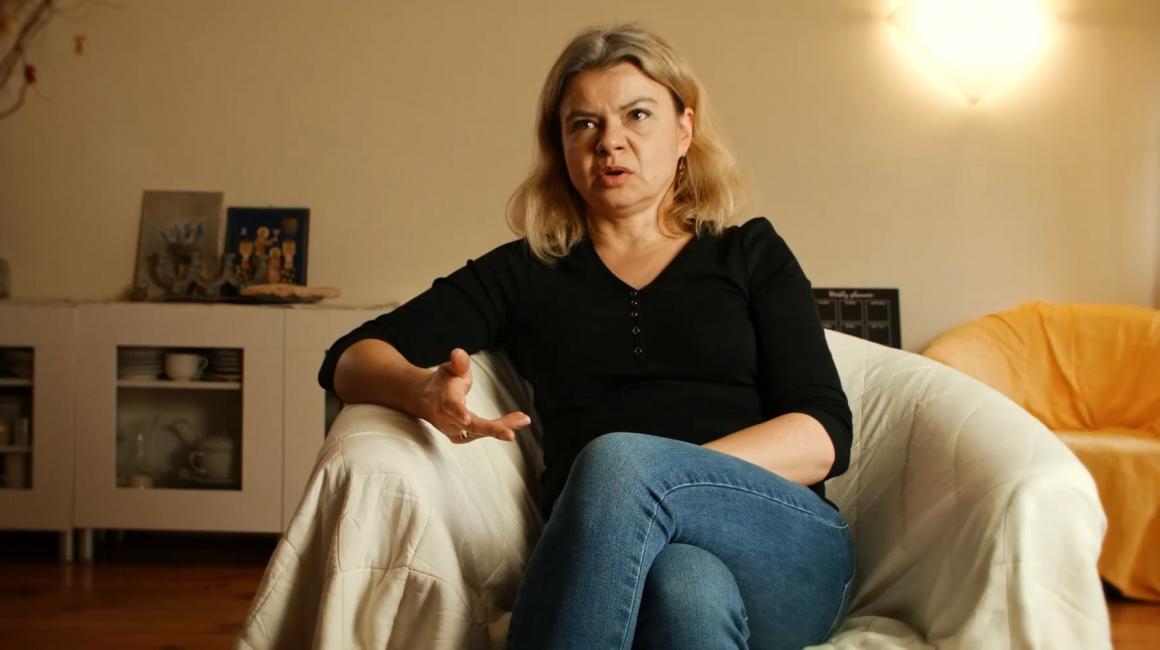 Kobieta siedzi na fotelu i coś mówi.