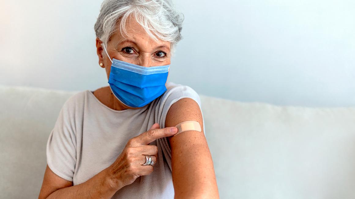 Starsza pani pokazuje, że jest po szczepieniu