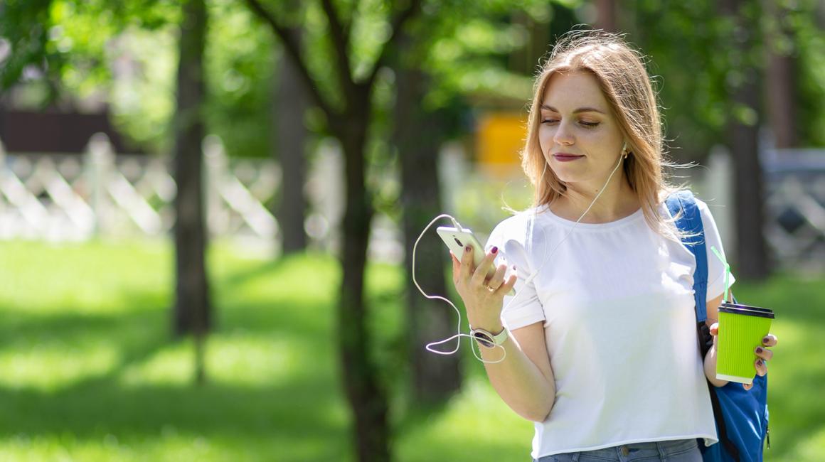 Kobieta na spacerze patrzy na komórkę