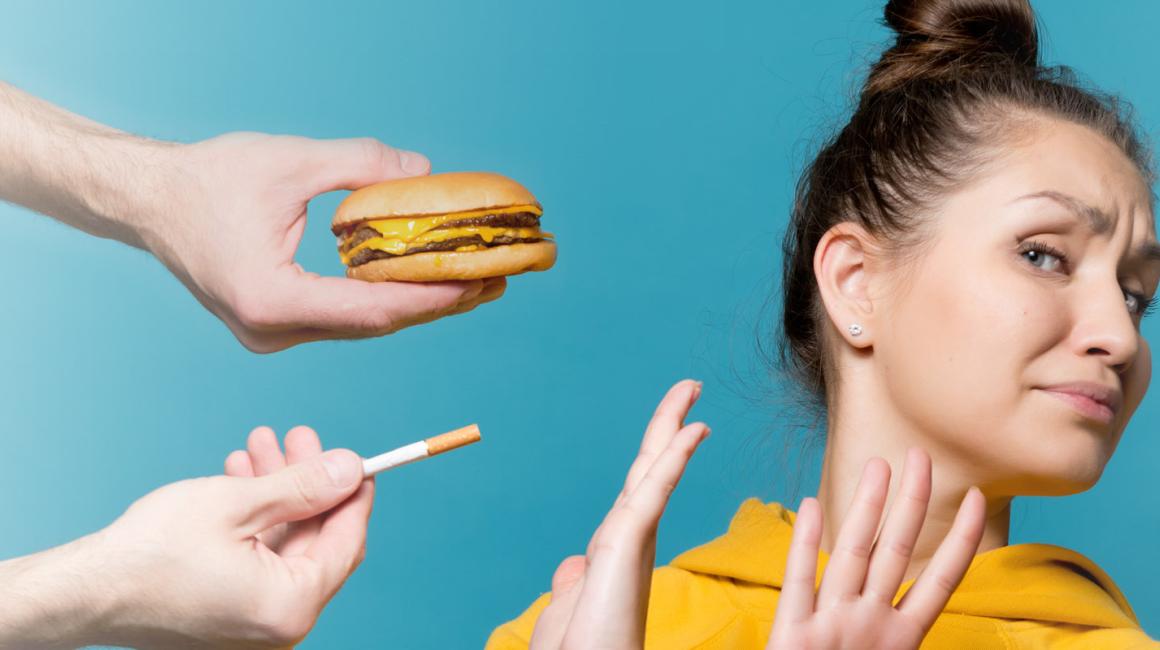 Kobieta odwraca głowę i krzyżuje ręce na znak protestu przed papierosem, fast foodem i alkoholem.