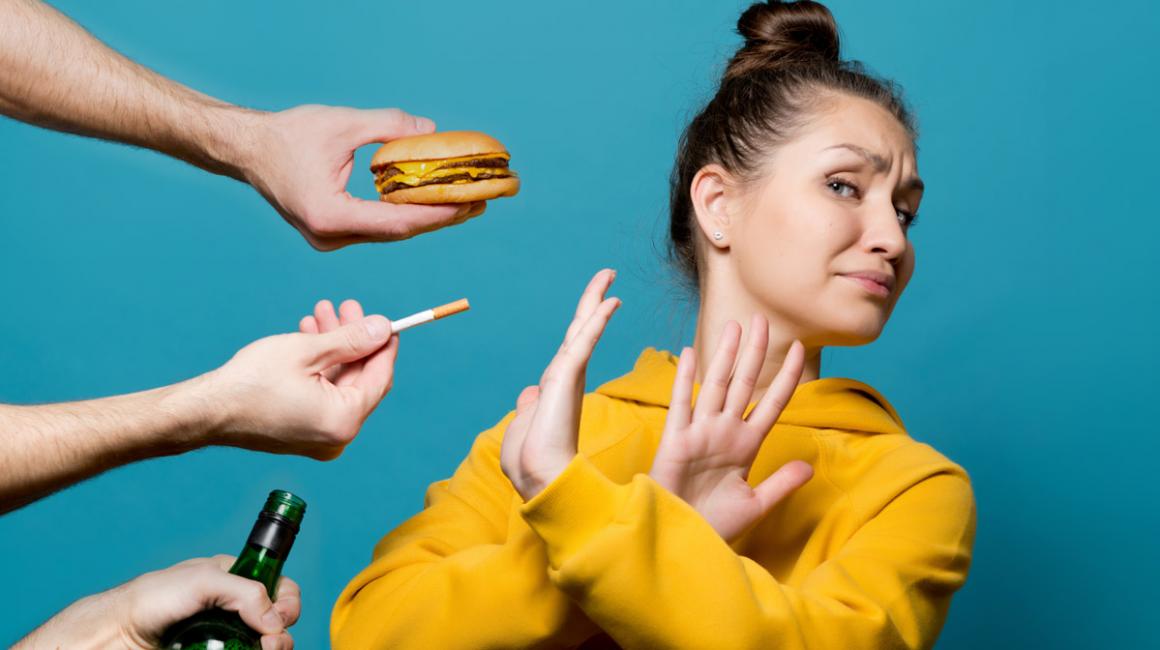 Kobieta odwraca głowę i krzyżuje ręce na znak protestu przed papierosem, fast foodem i alkoholem.
