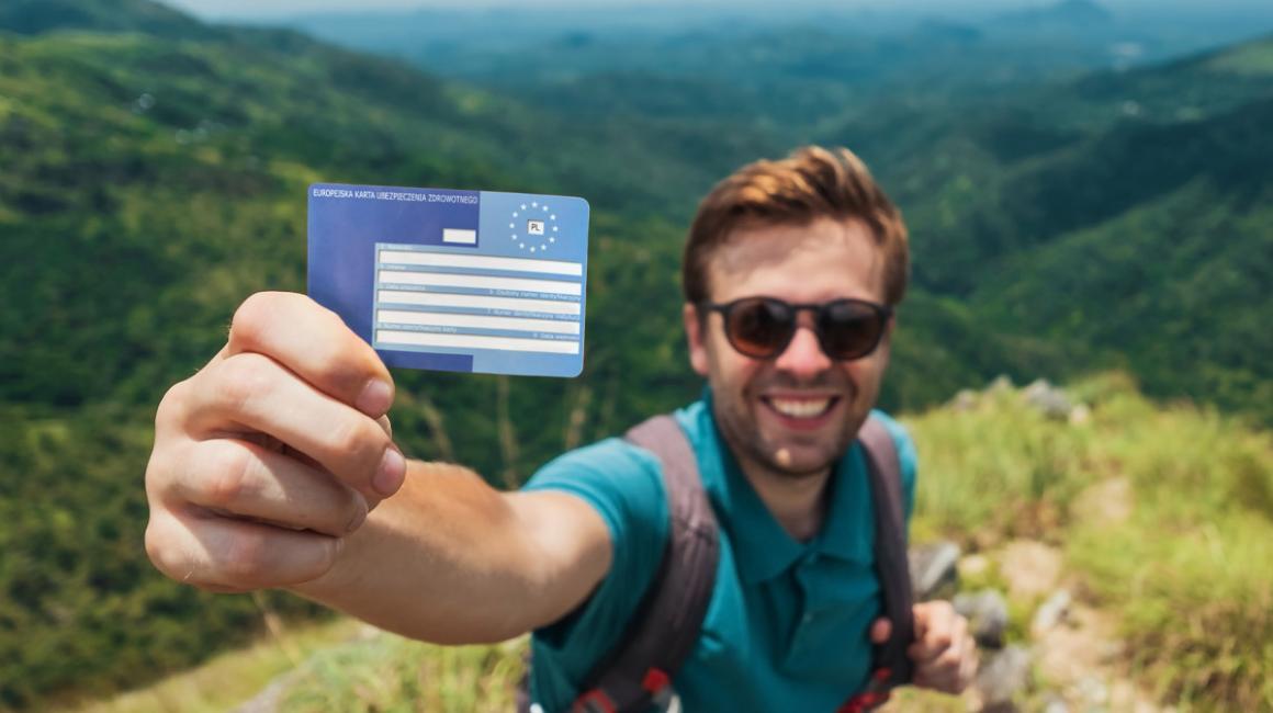 Turysta pokazujący kartę EKUZ. W tle góry