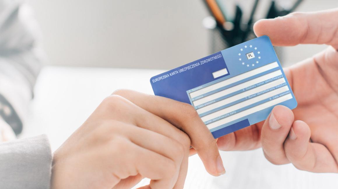 Zbliżenie na ręce. Pacjent podaje lekarzowi swoją kartę EKUZ.